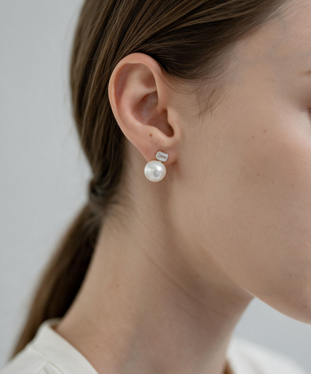 Model with a low ponytail wearing the silver 10mm shell pearl and baguette cut zirconia drop earrings