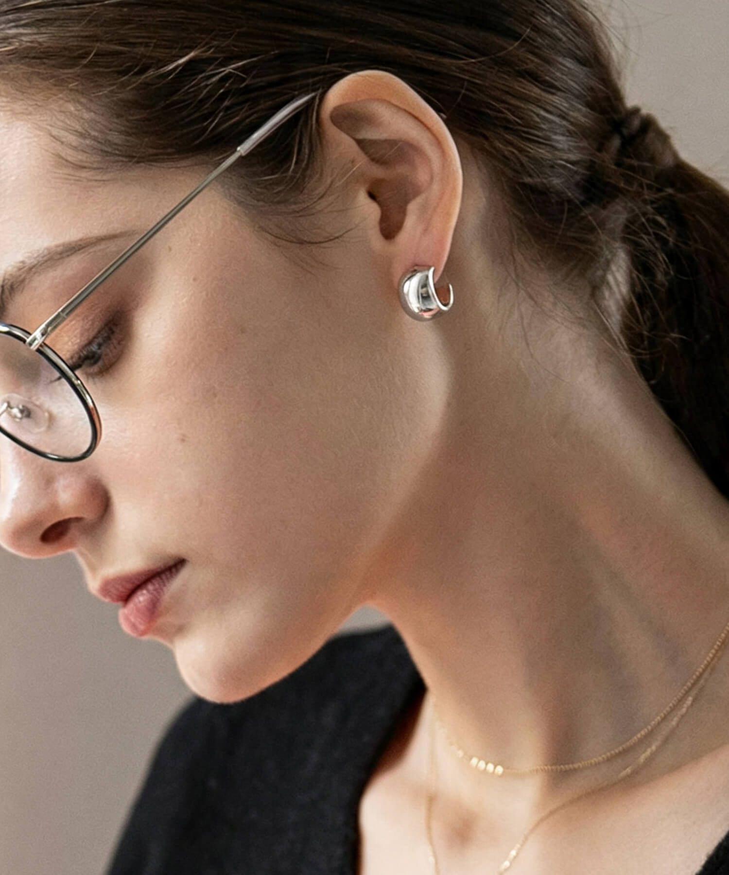 C-curve silver hoop earrings hugging the earlobe