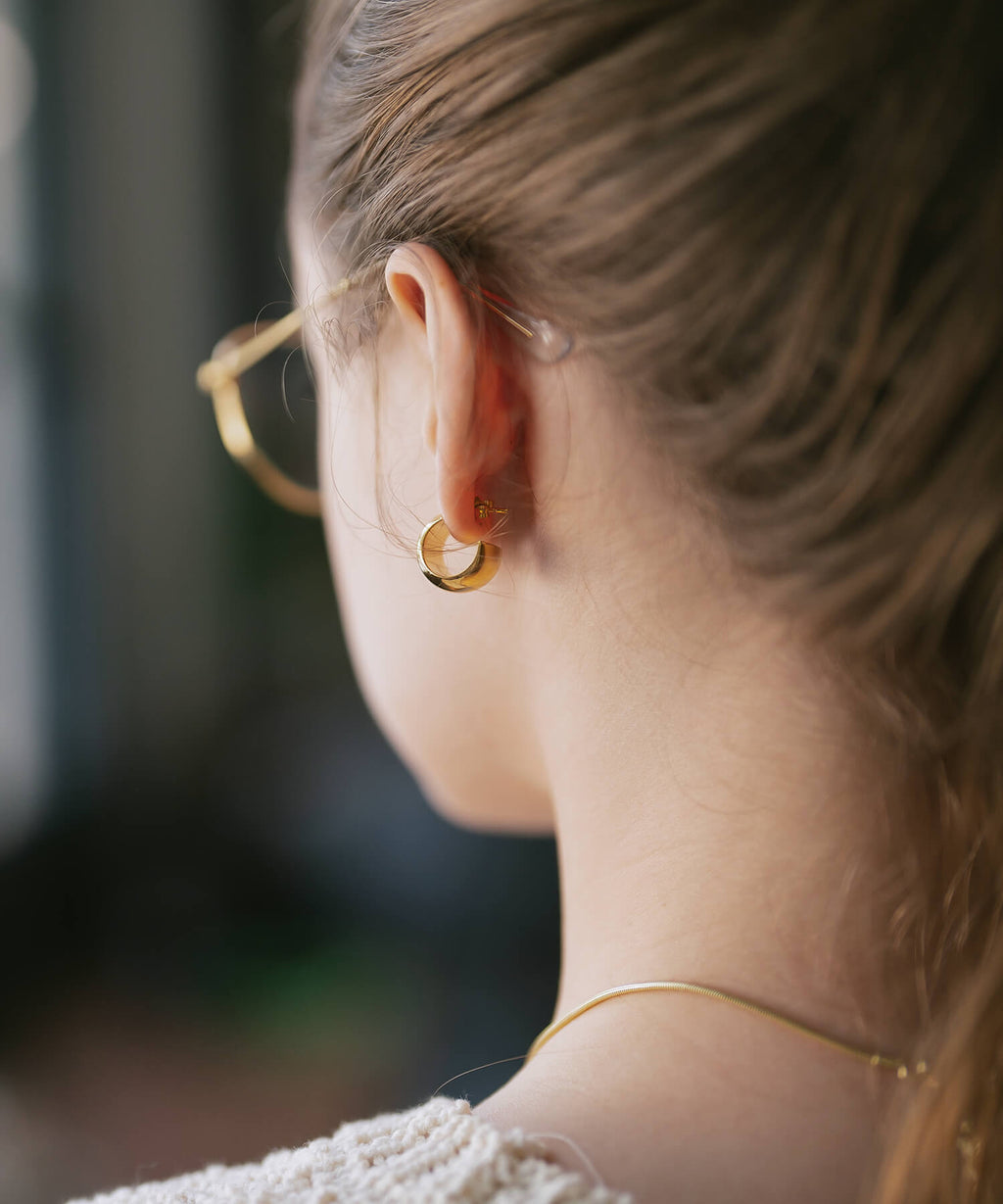 Gold barrel earrings close-up on the ear