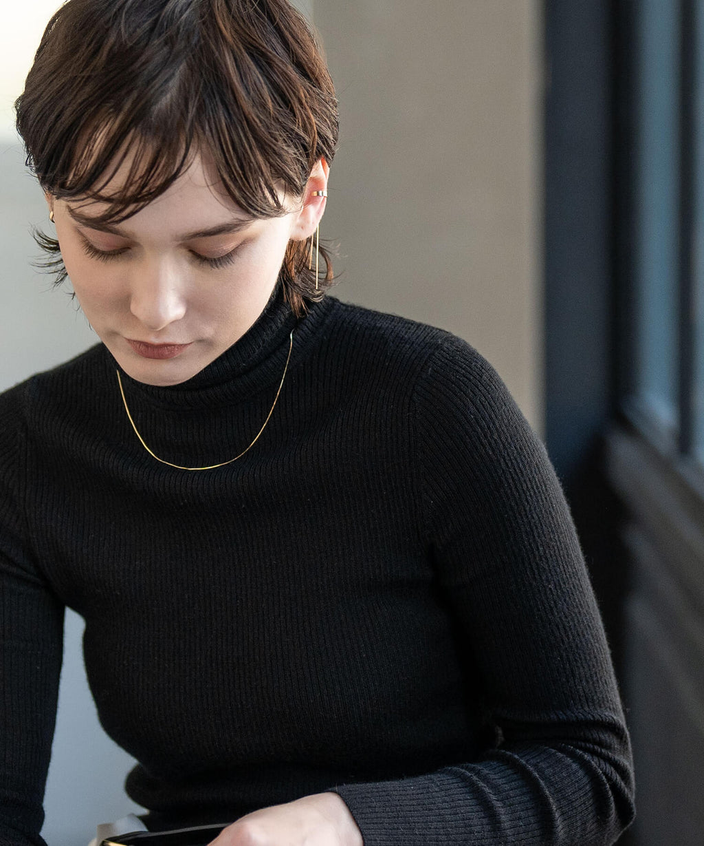 10K gold chain ear cuff worn with a black turtleneck