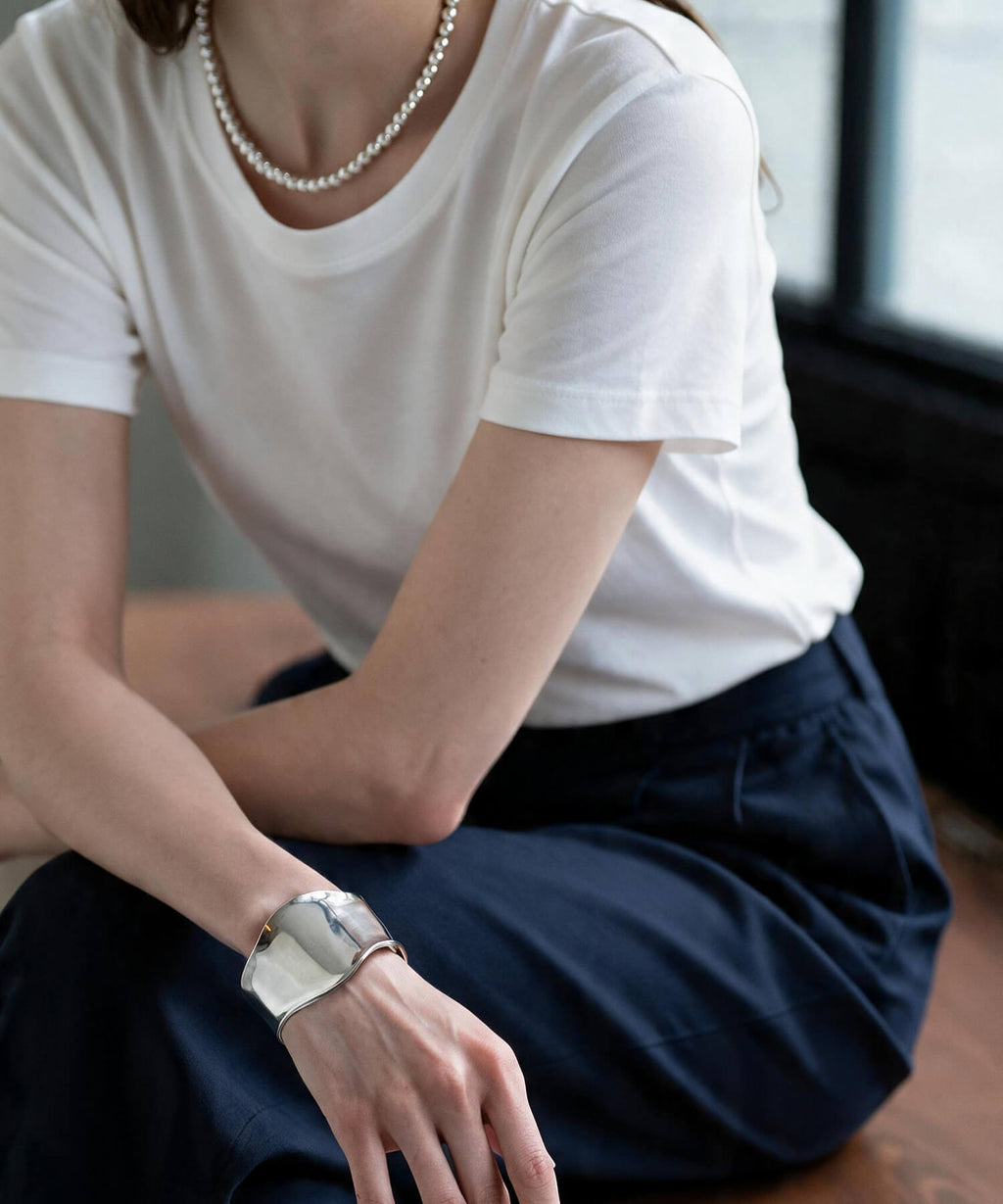 Wave-edge wide silver cuff bangle worn on the wrist