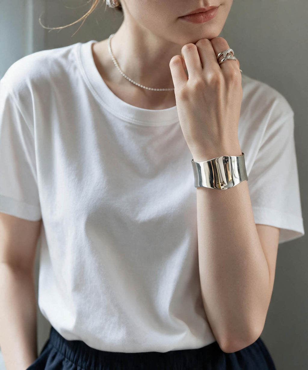 Wave type broad silver bangle worn with a shirt