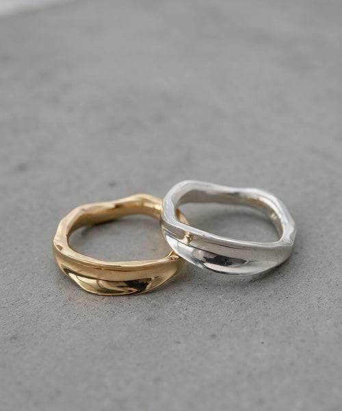 Silver and gold ripple wave rings side by side in soft daylight