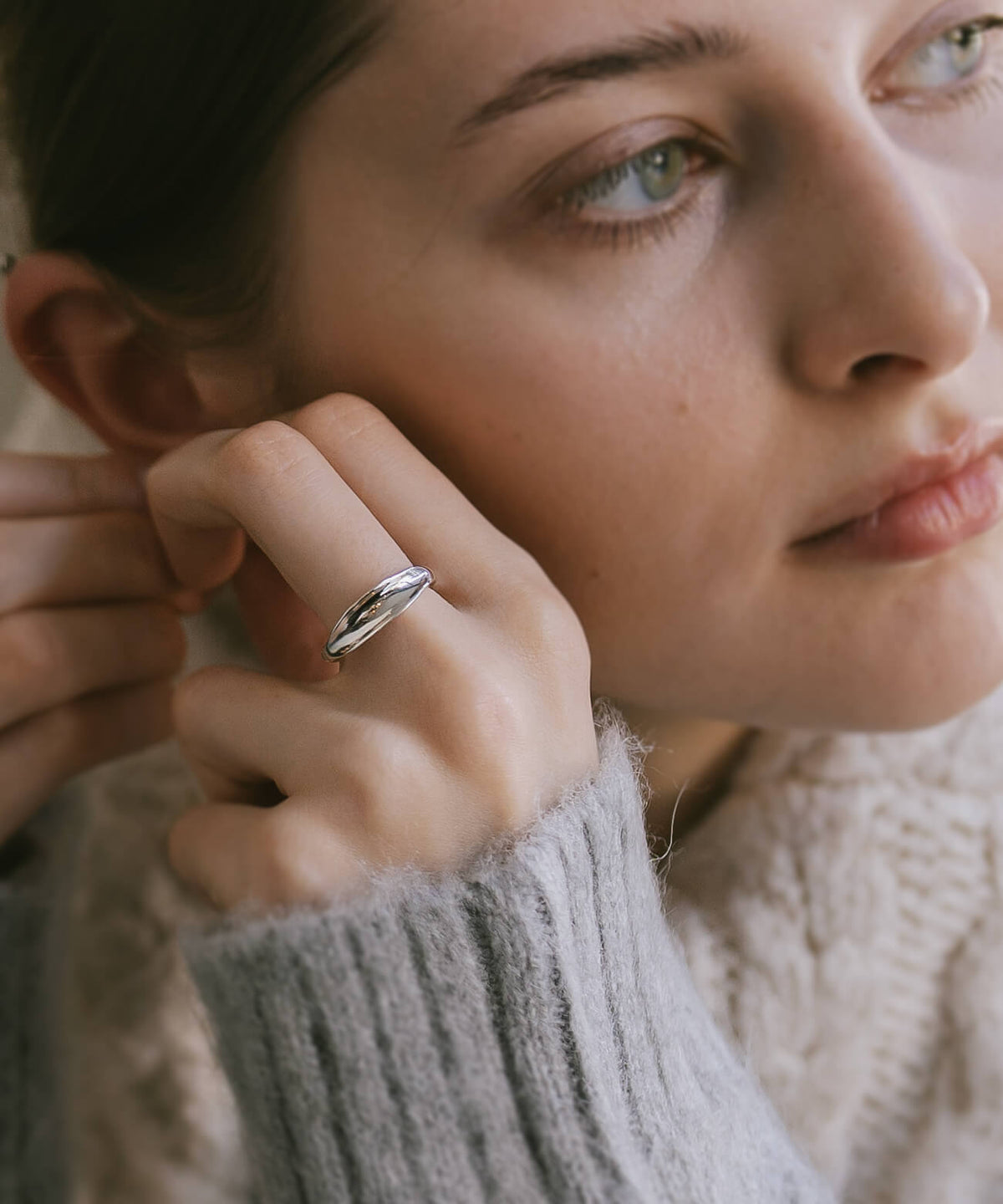 Model's face and hand wearing the sterling silver ripple wave ring