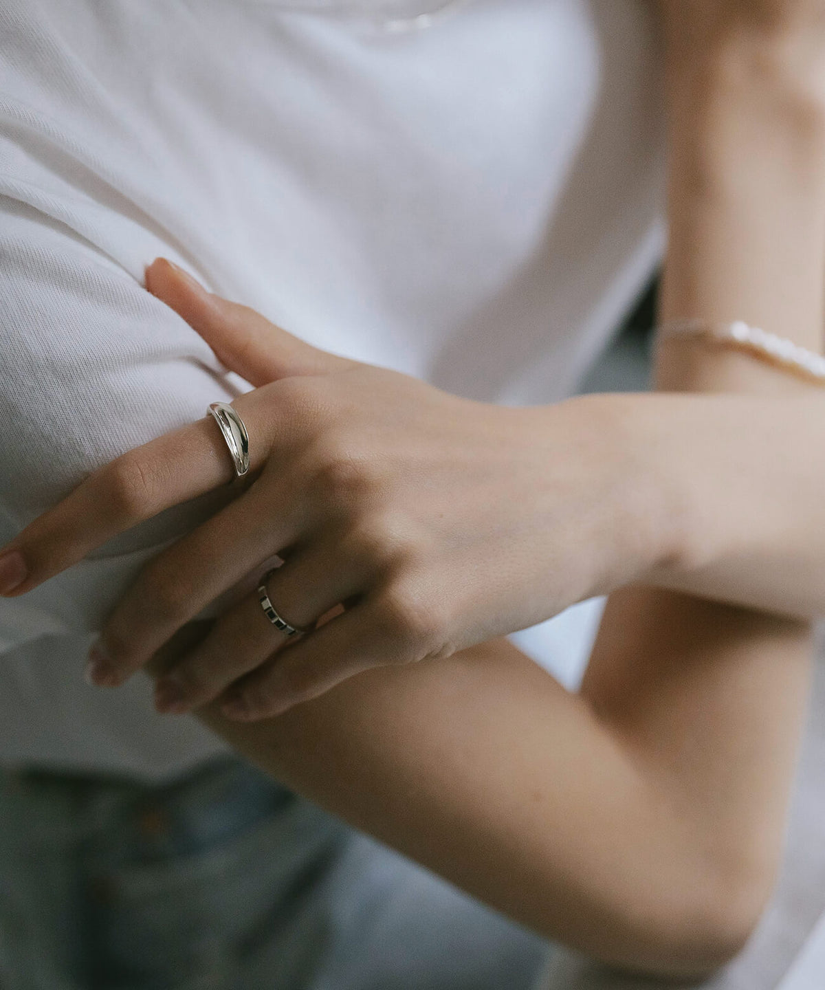 Hand resting on the arm, wearing the sterling silver ripple wave ring