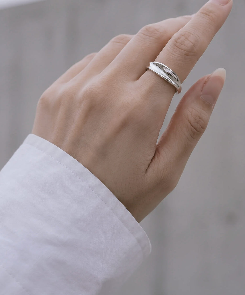 Hand emerging from a white shirt cuff, wearing the sterling silver ripple wave ring