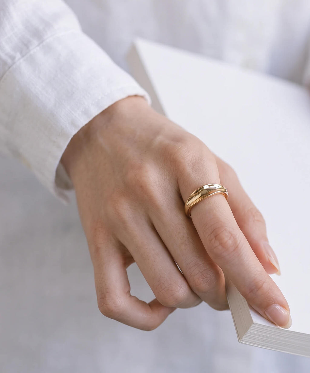 Hand from a white shirt cuff wearing the 18K gold plated ripple wave ring