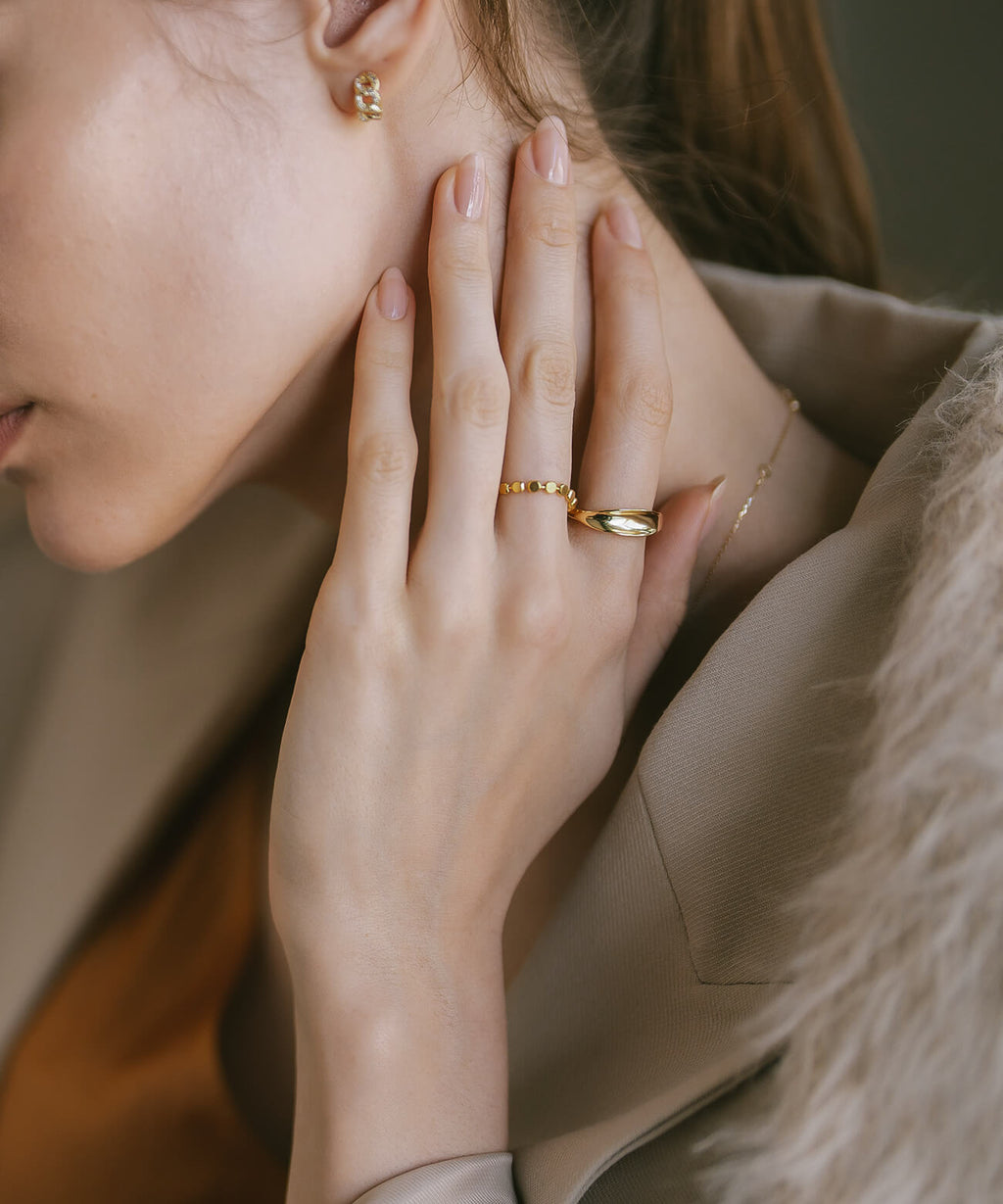 Hands raised near the face wearing the 18K gold plated ripple wave ring