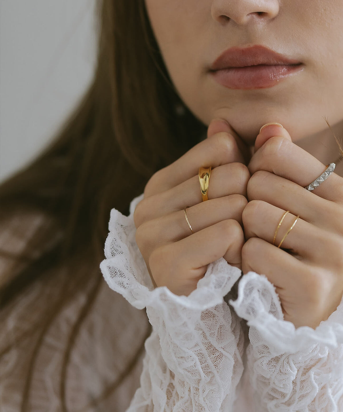 Hands clasped under the chin wearing the 18K gold plated ripple wave ring