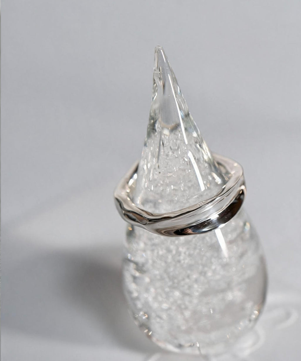 Sterling silver ripple wave ring resting on a clear glass ring cone