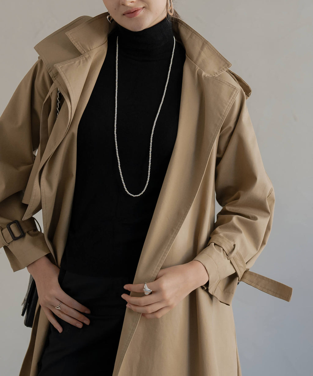 Long silver ball chain necklace worn full length with a beige trench coat