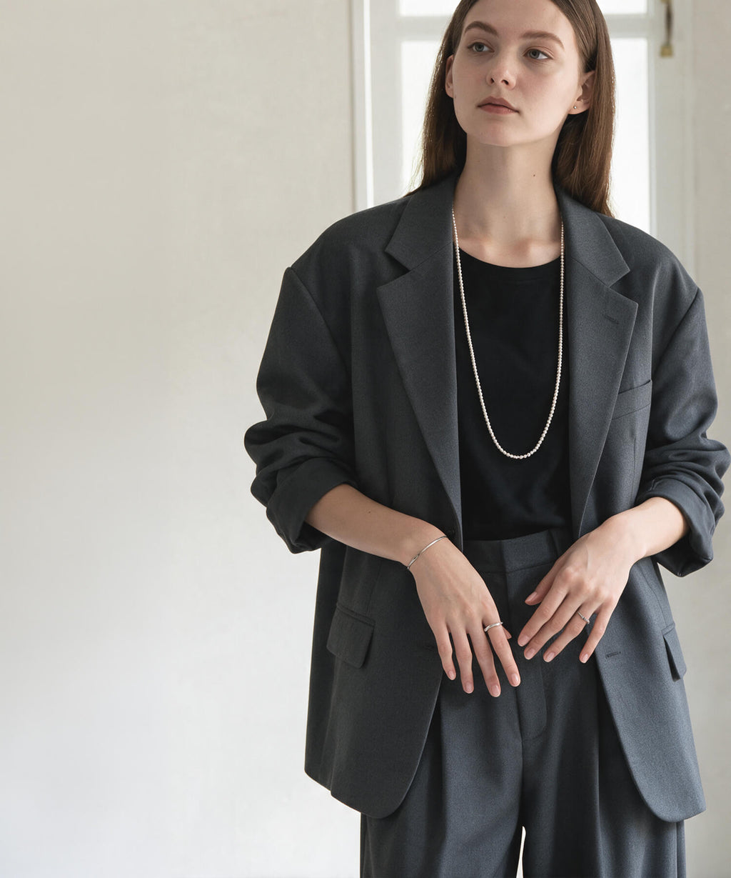 Long silver ball chain necklace with a charcoal grey tailored suit