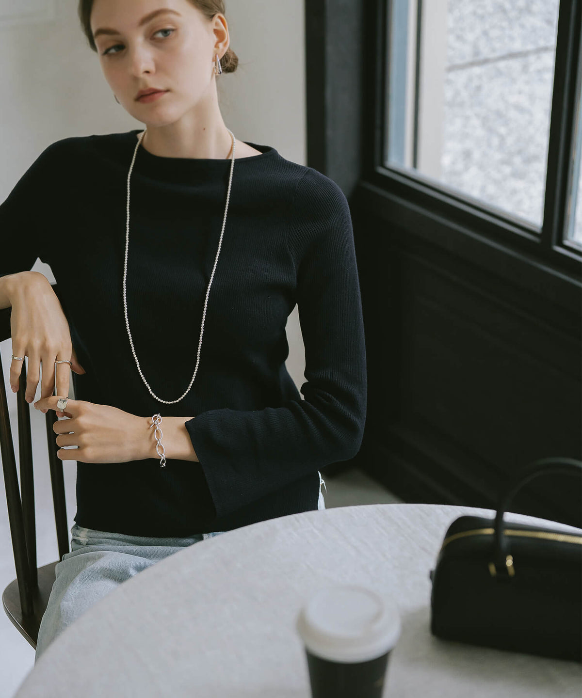 Long silver ball chain necklace with a black knit top