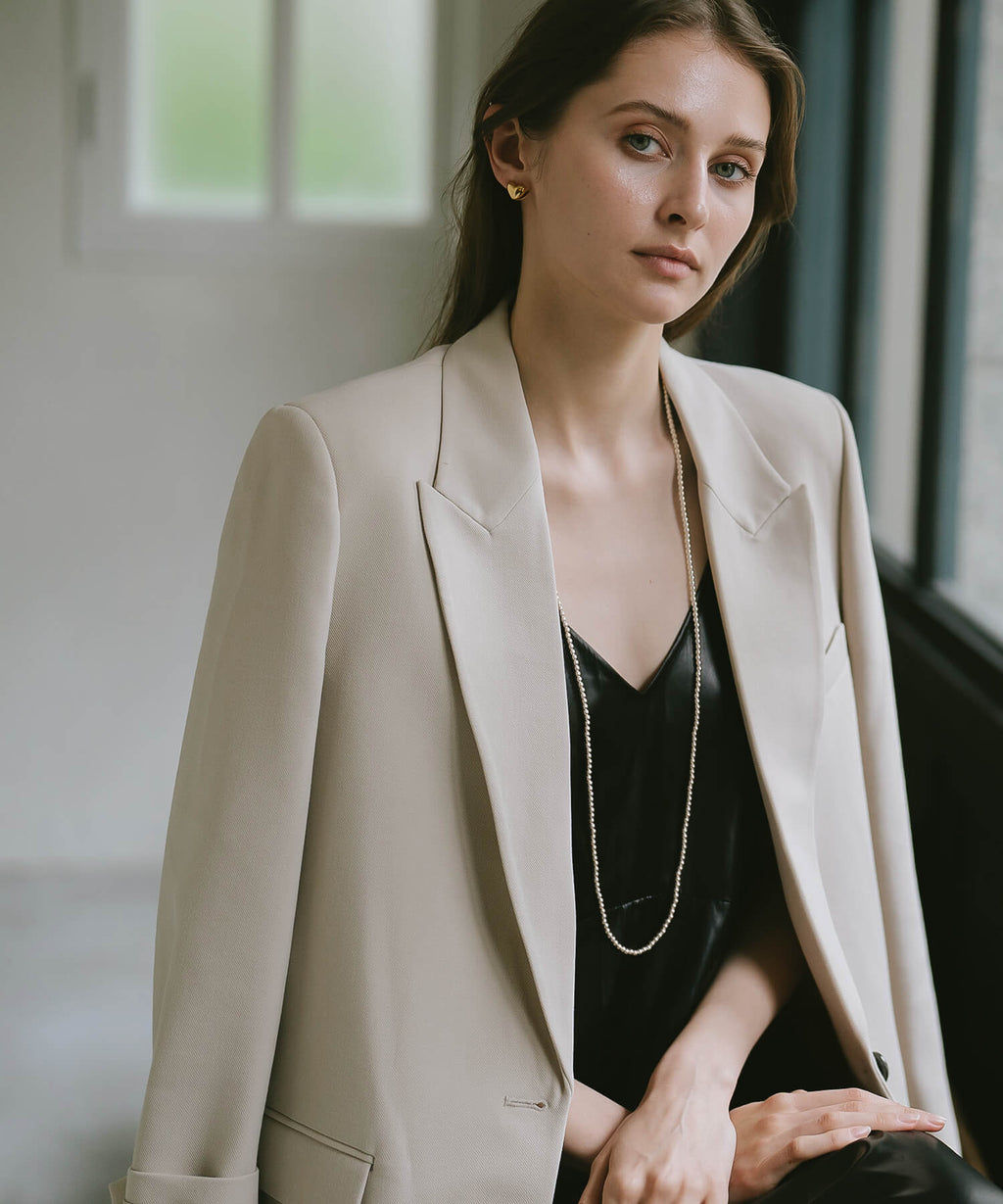 Long silver ball chain necklace with an ivory jacket over a black camisole
