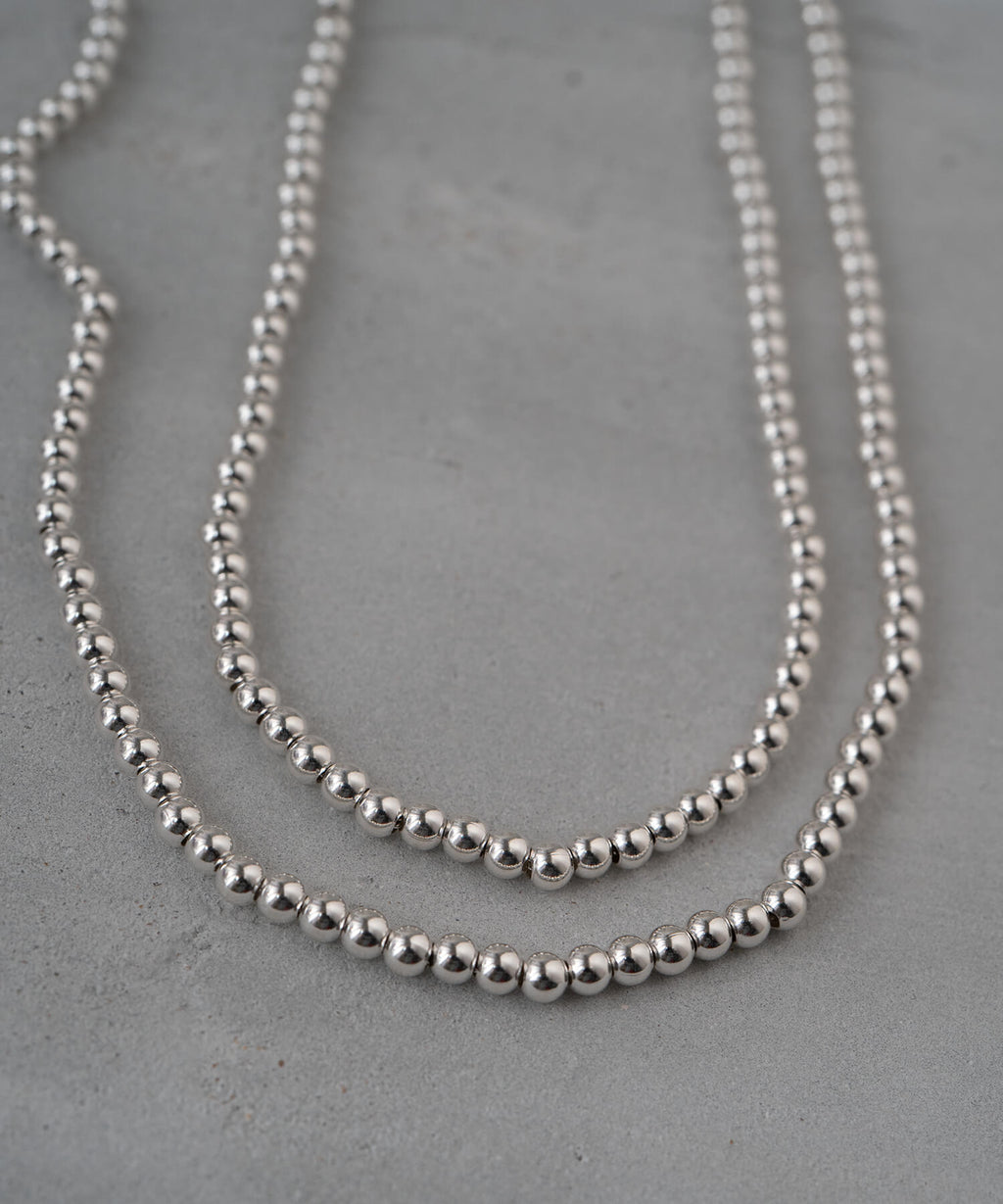 Close up of the doubled silver ball chain on a concrete surface