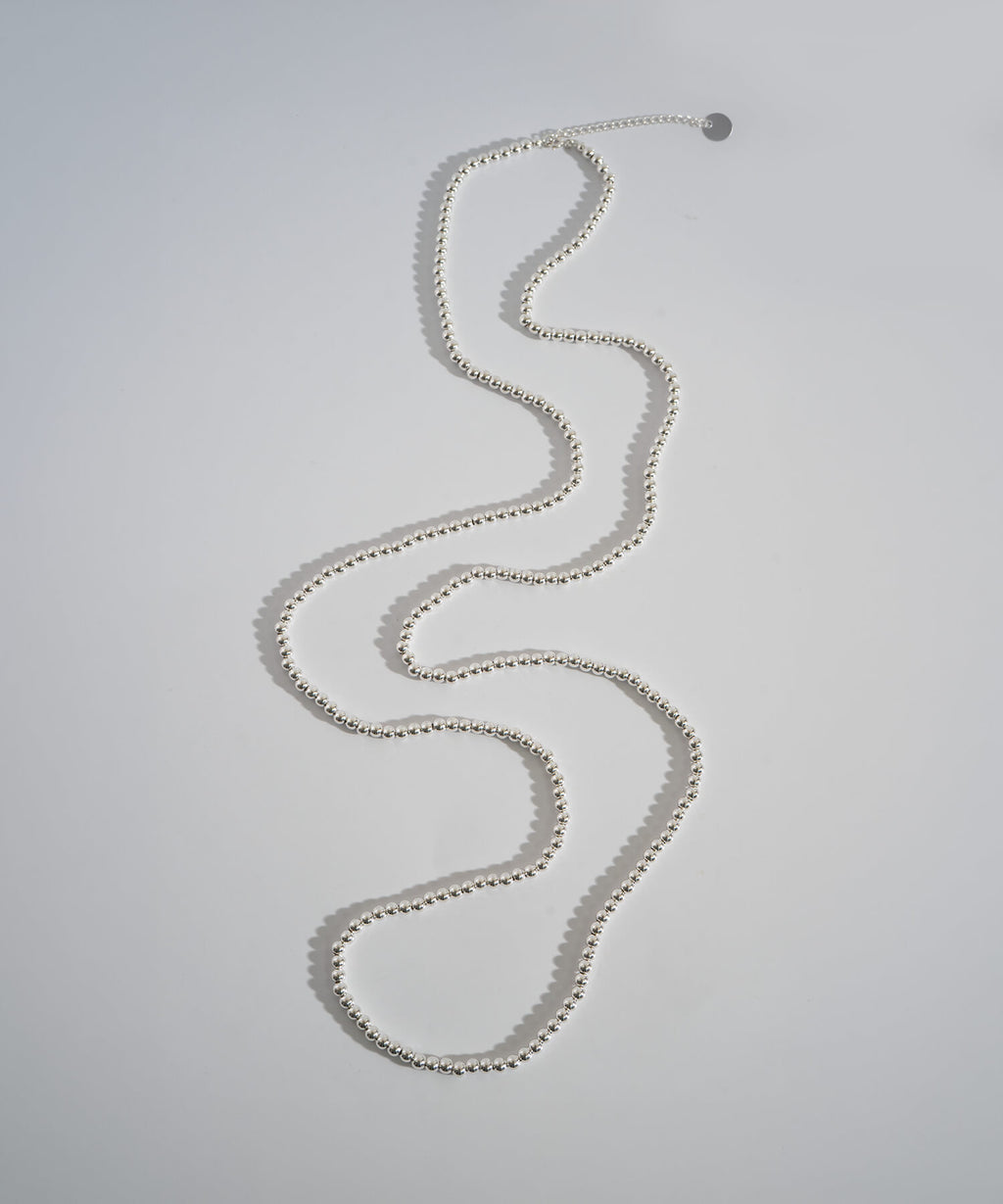 Silver ball chain necklace laid in a winding line