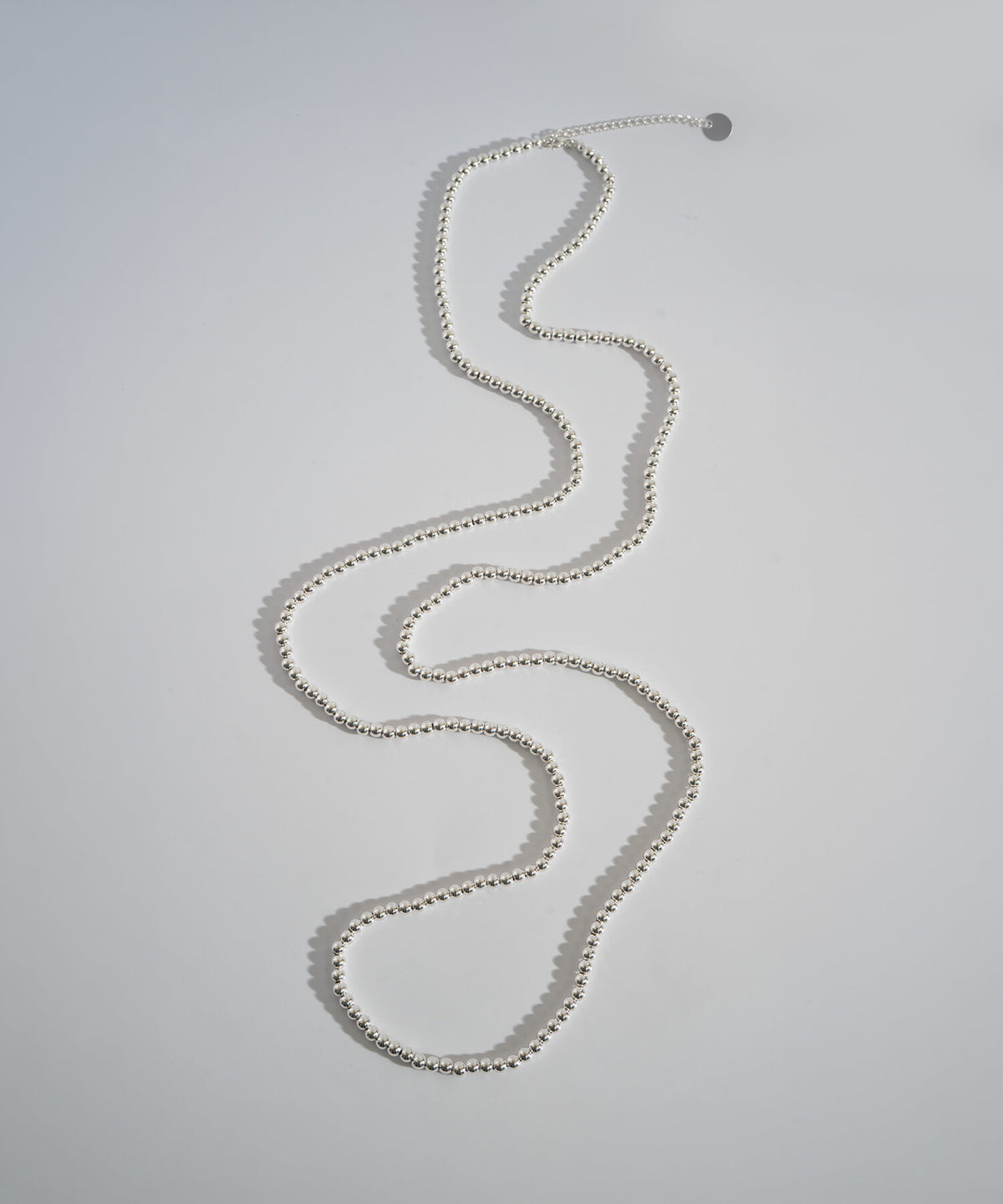 Silver ball chain necklace laid in a winding line