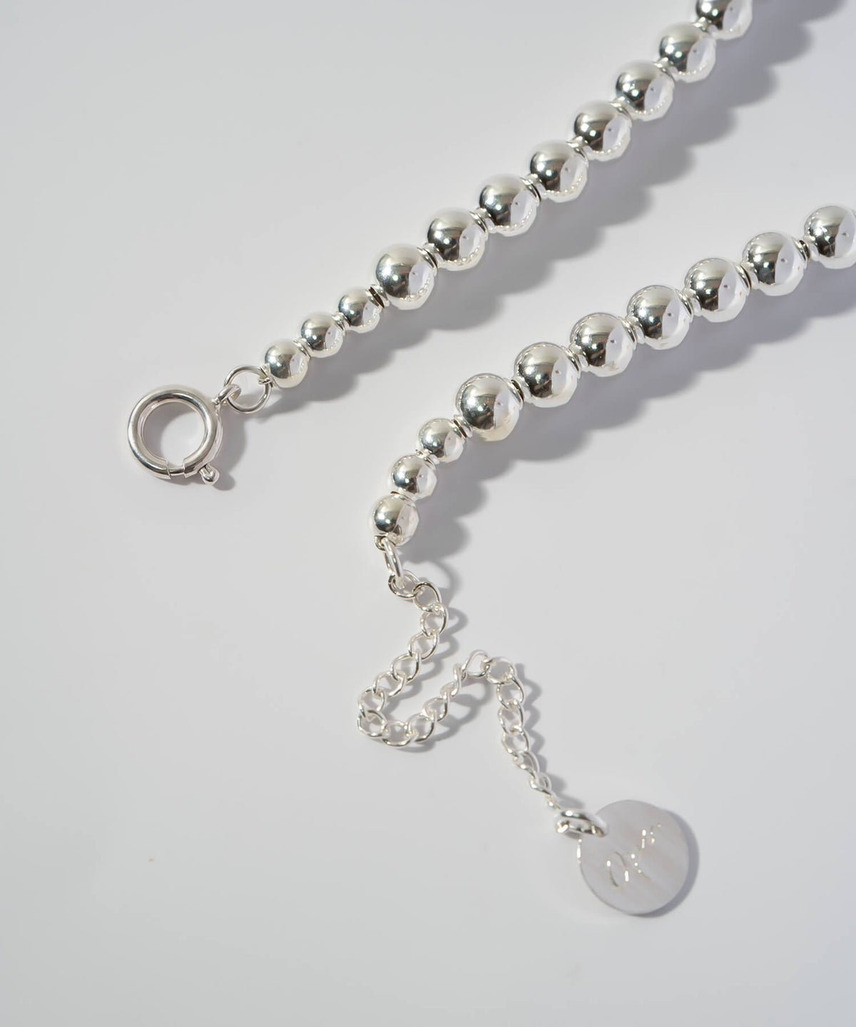 Clasp, adjuster chain and logo tag detail