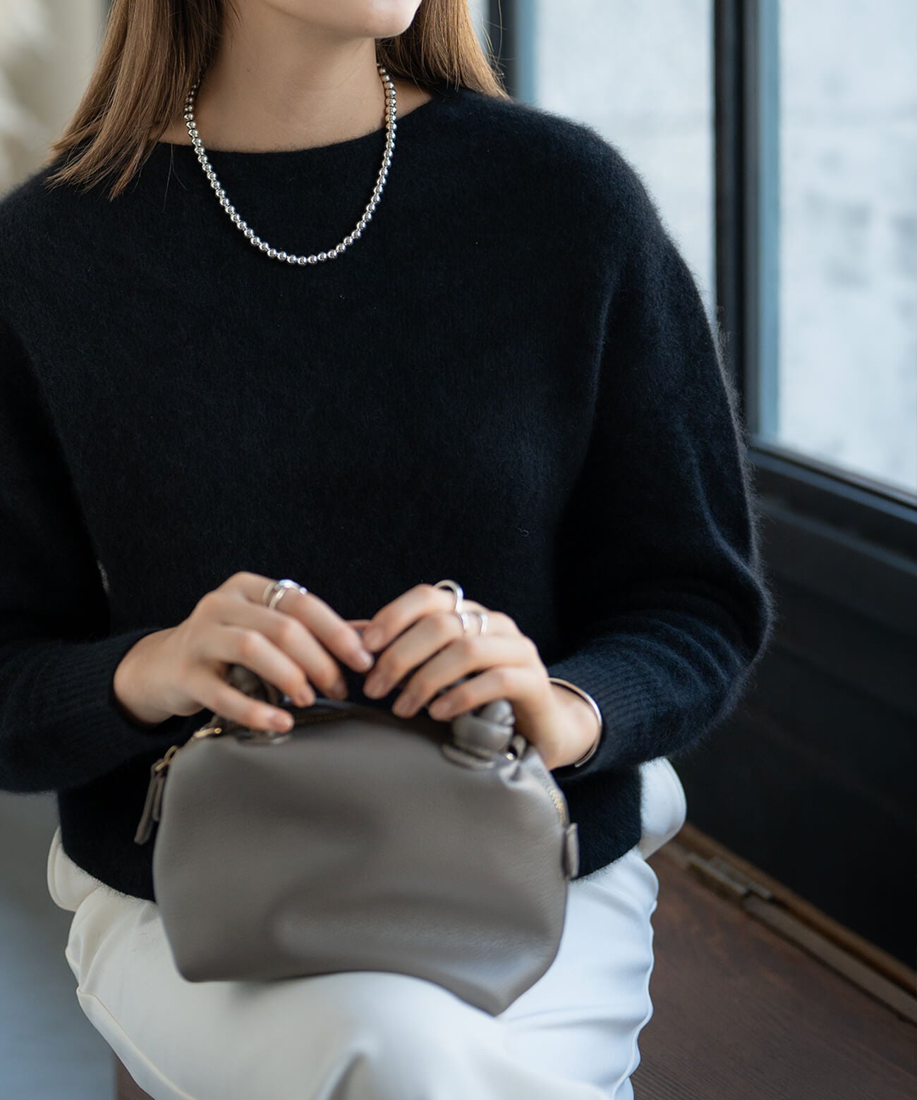Sterling silver ball chain necklace with a black knit and handbag