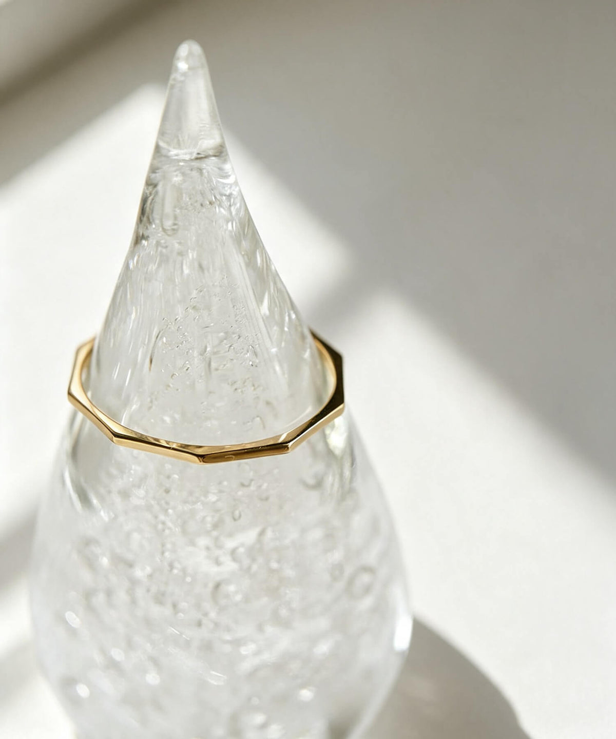 18K gold decagon skinny ring resting on a glass ornament