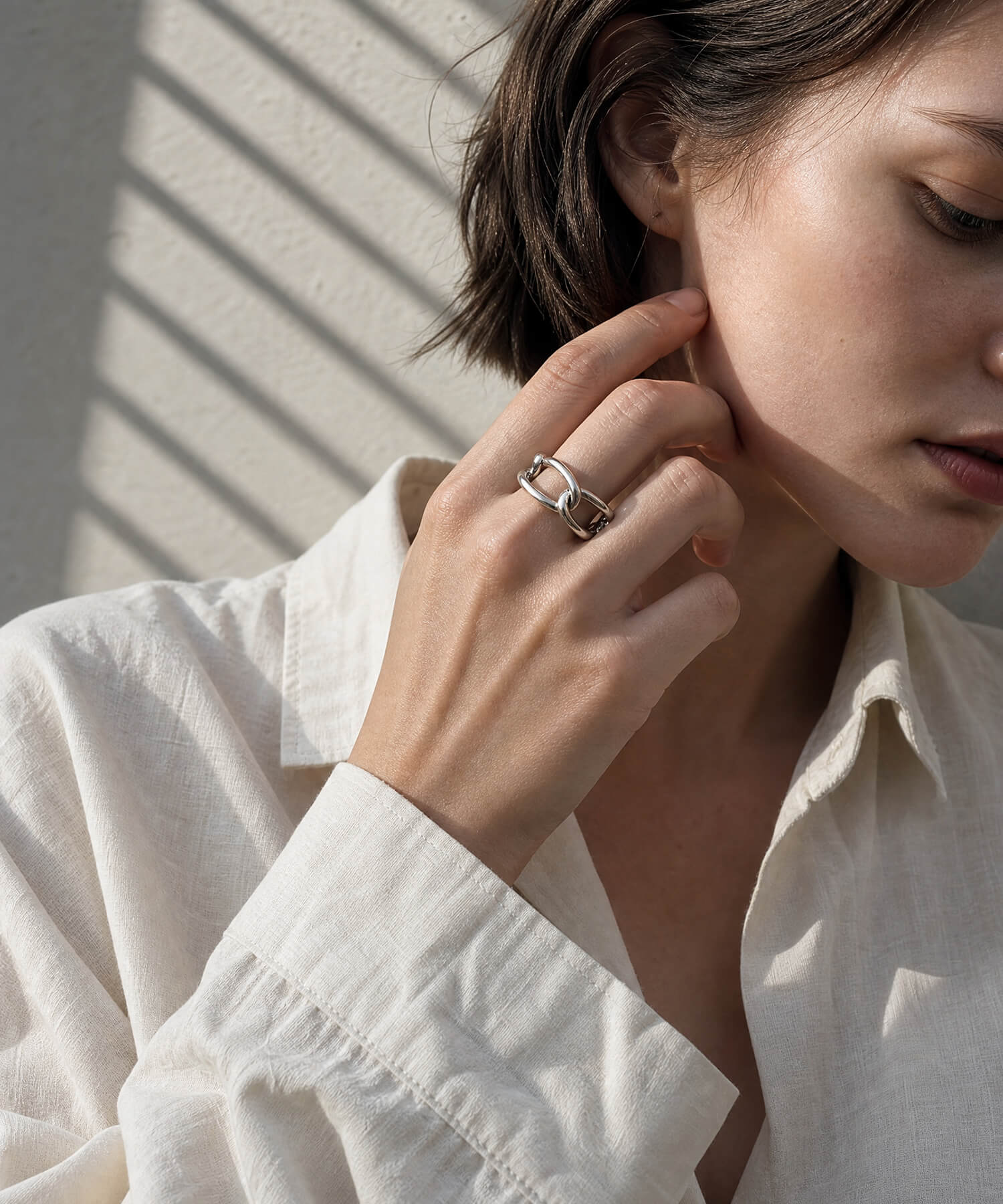 Model in a white shirt wearing the sterling silver chunky chain ring, hand raised to her ear