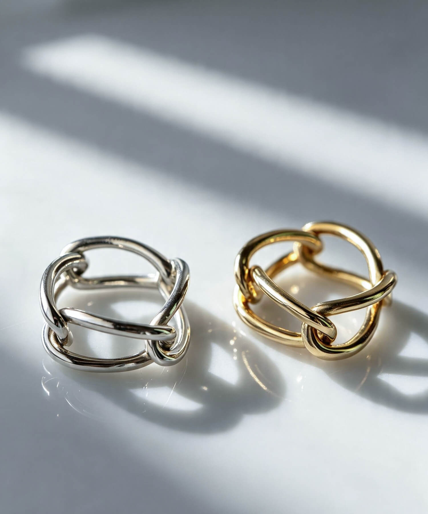Silver and gold chunky chain rings side by side in soft sunlight