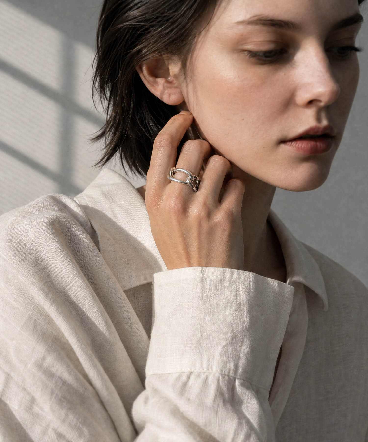 Model in a white shirt and beige coat wearing the sterling silver chunky chain ring
