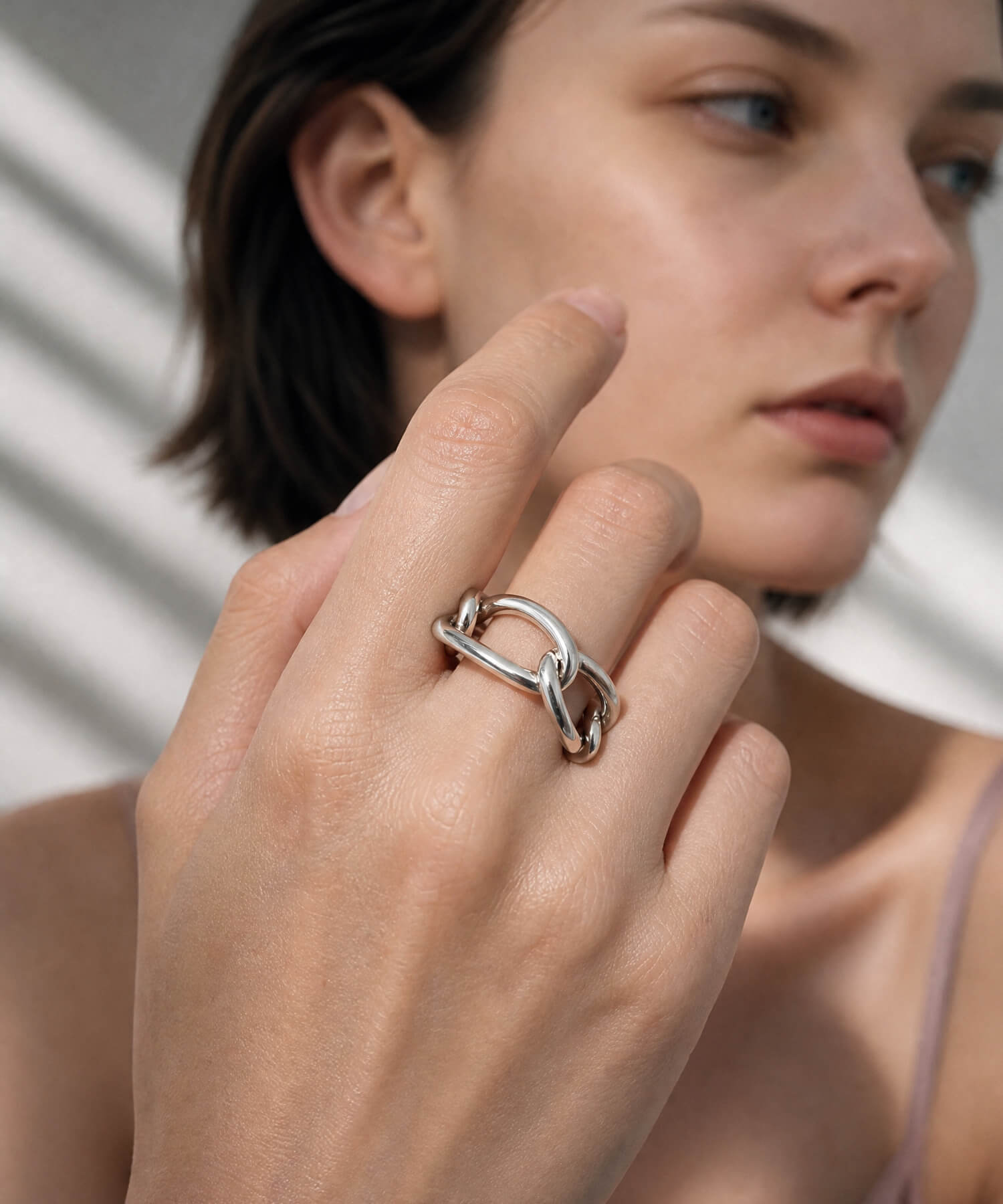 Close up of a hand wearing the sterling silver chunky chain ring beside the face