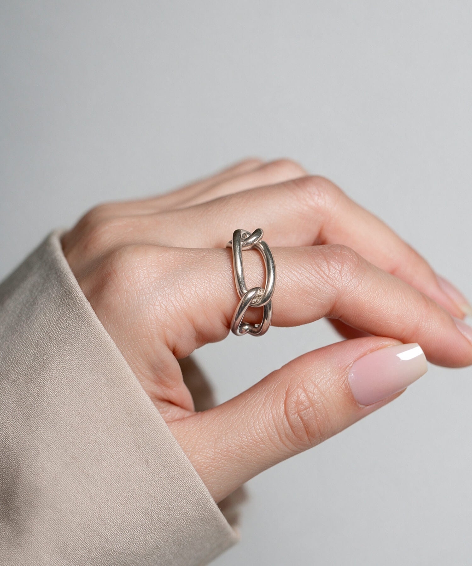 Hand resting on a linen sleeve wearing the sterling silver chunky chain ring