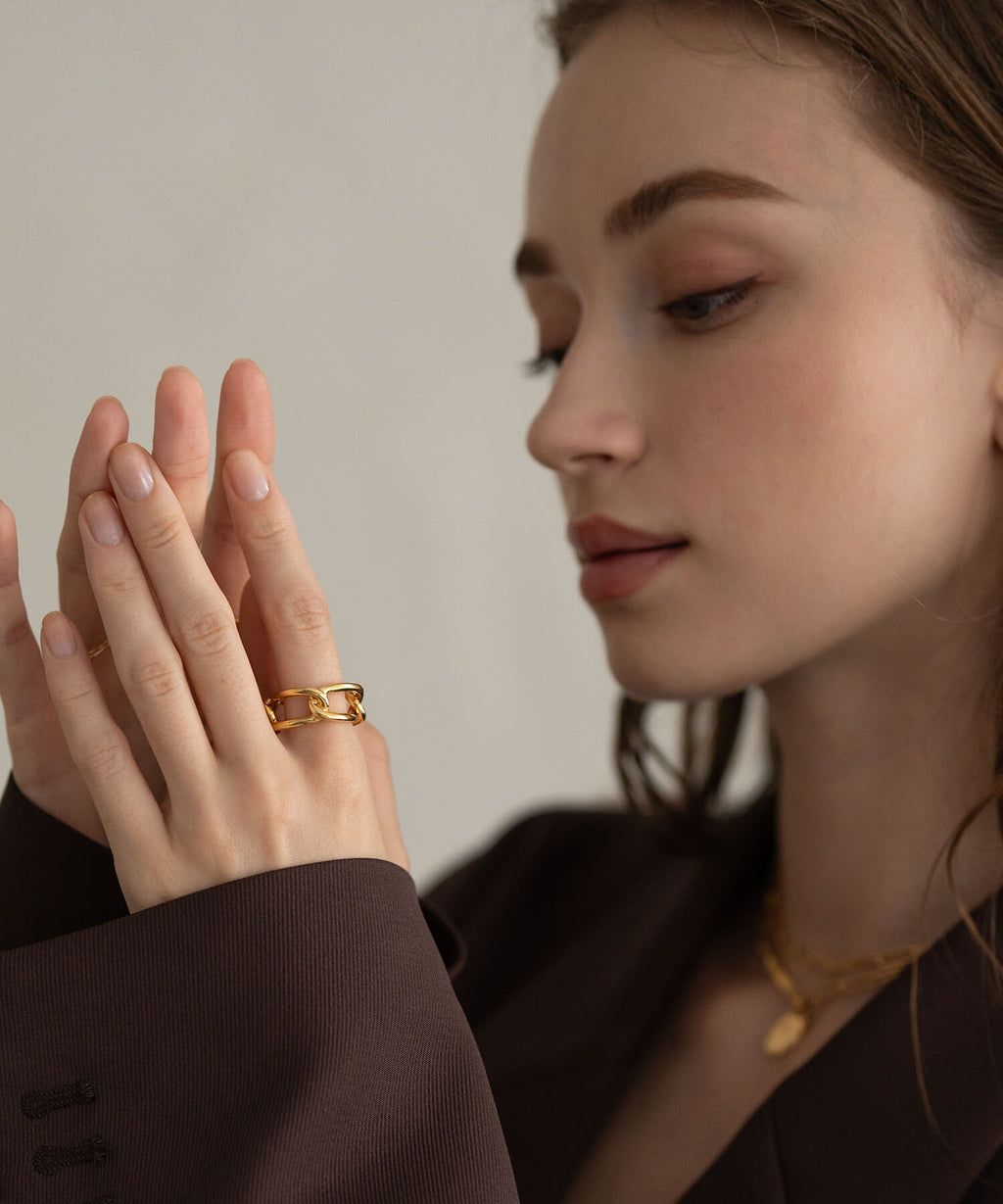 Model in a brown jacket wearing the 18K gold plated chunky chain ring