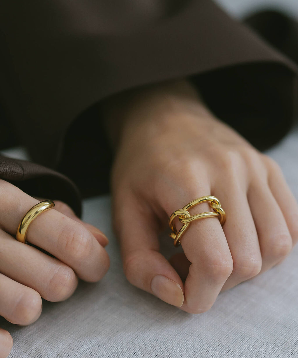 Hands on linen wearing two 18K gold plated chunky chain rings
