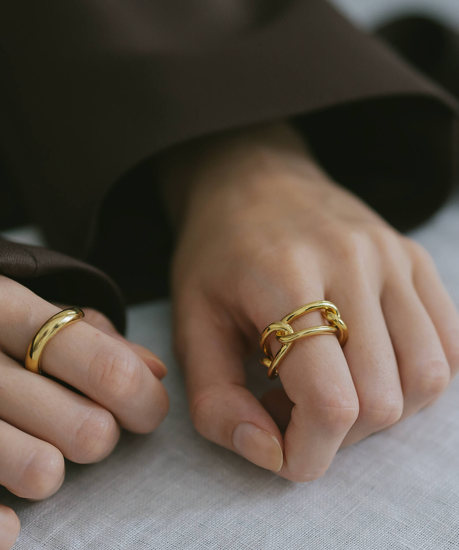 Hands on linen wearing two 18K gold plated chunky chain rings