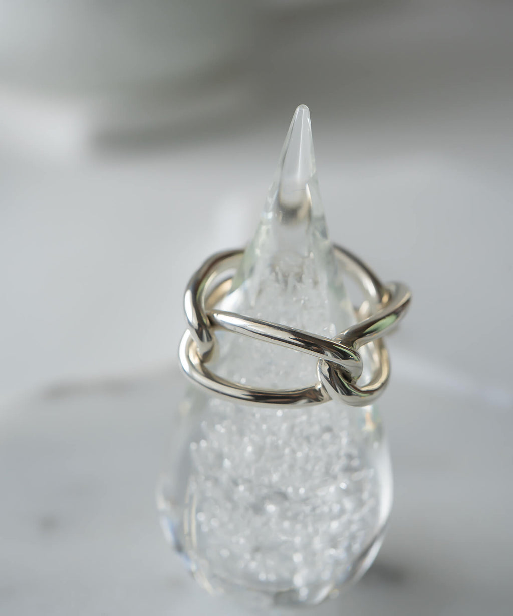The sterling silver chunky chain ring placed on a clear glass object