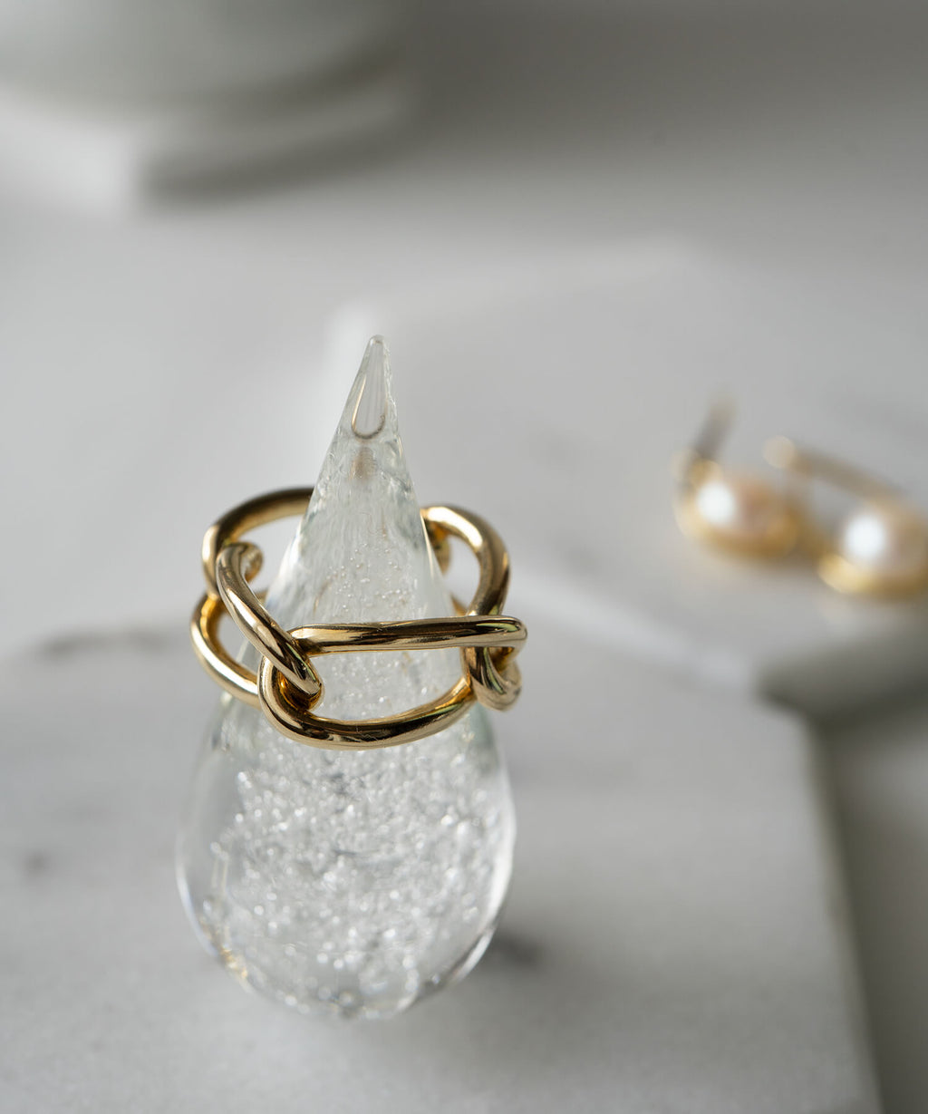18k gold plated chunky chain ring placed on a clear glass object