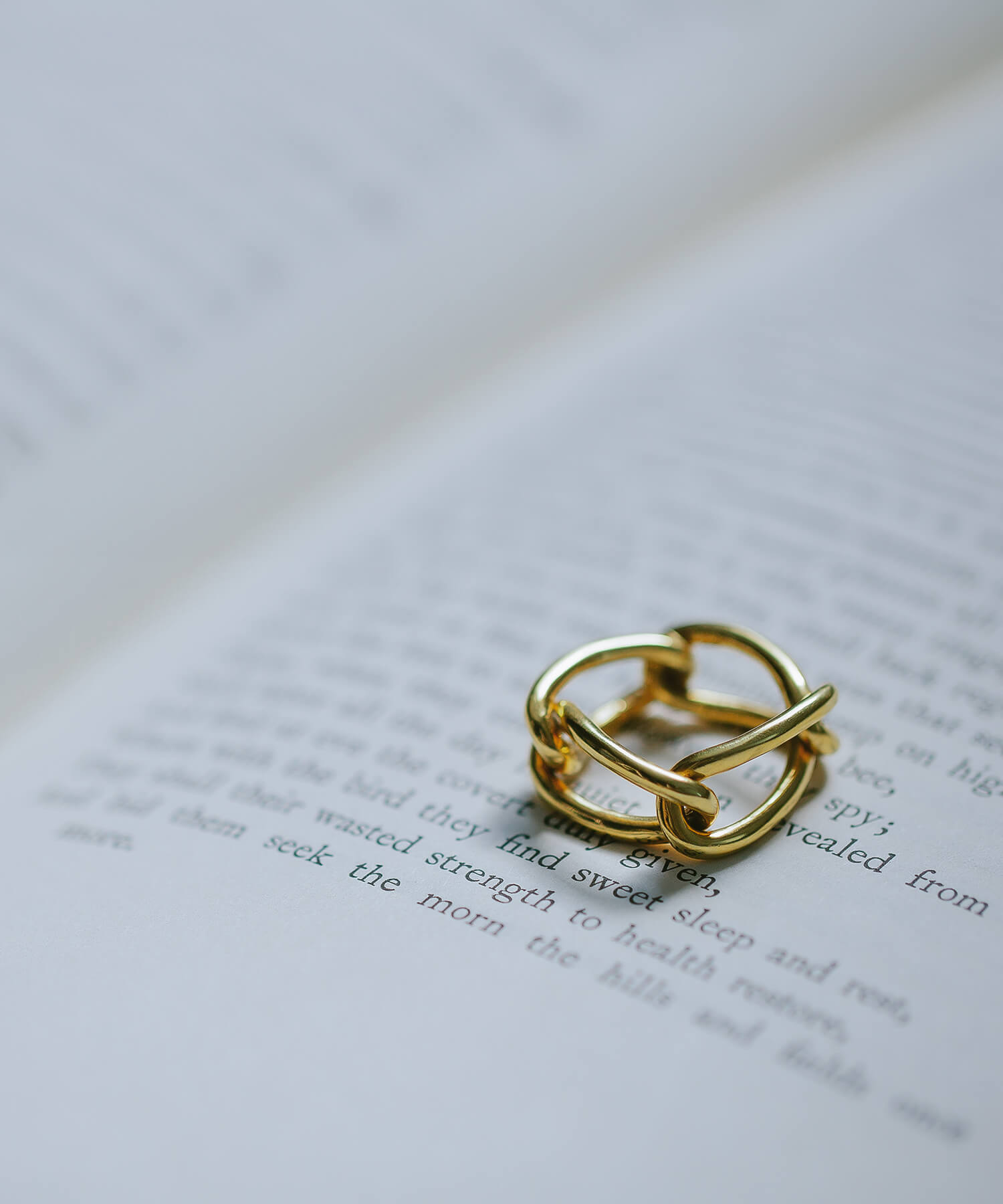 18k gold plated chunky chain ring resting on an open book